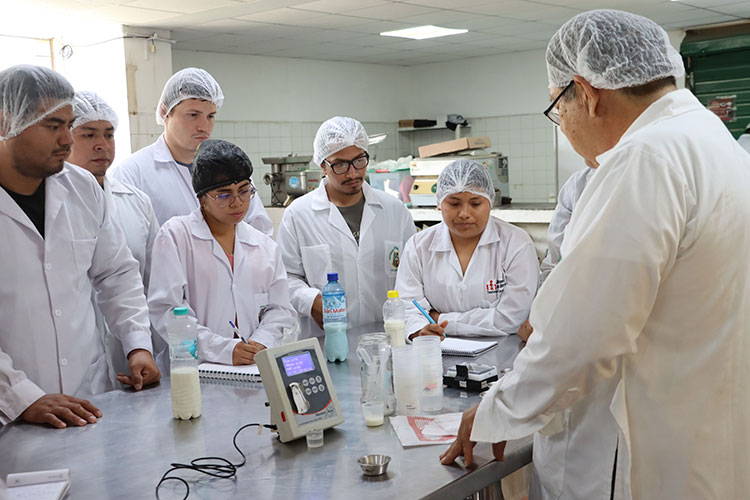 Estudiantes de Zootecnia y docente analizan muestras lácteas usando un equipo de medición digital en el laboratorio especializado