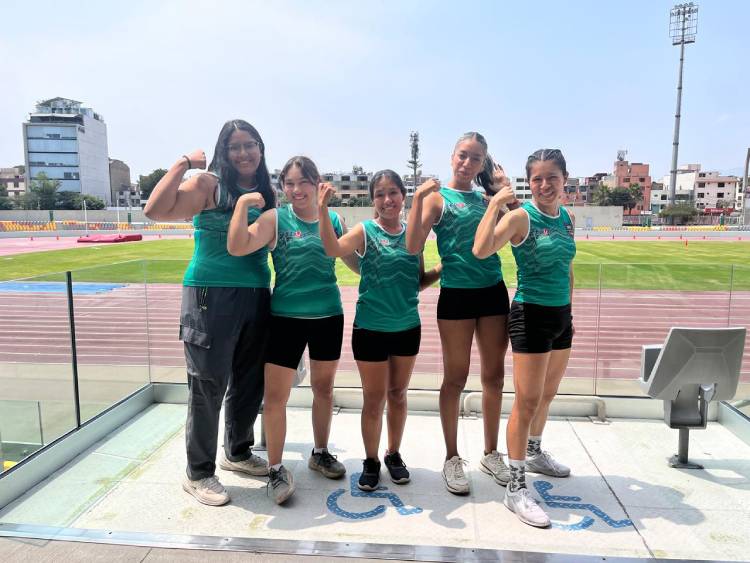 Cinco atletas femeninas de la delegación UNALM flexionan los brazos en señal de fortaleza en las tribunas de la VIDENA