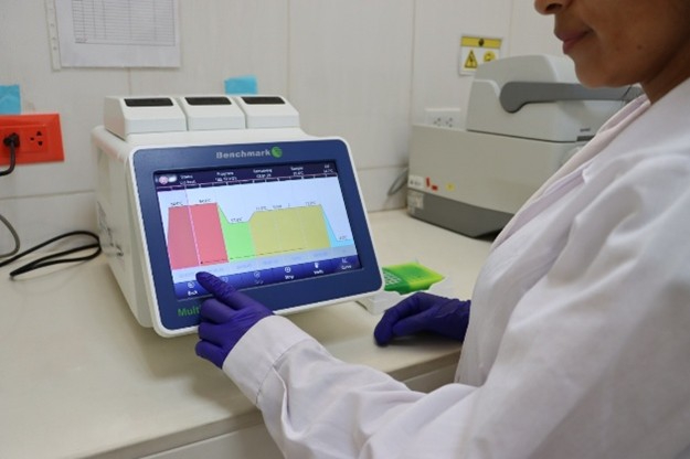 Termociclador multibloque en uso con laptop para análisis de ADN en laboratorio de biotecnología